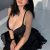 Woman with long dark hair sits on a bed in a black lingerie top and lace-trimmed skirt, smiling at the camera. Woman with long dark hair sits on a bed in a black lingerie top and lace-trimmed skirt, smiling at the camera.